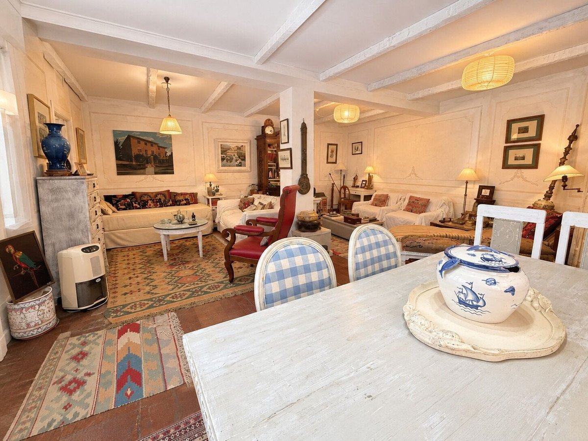 Spacious living and dining room with classic decor, featuring sofas, chairs, a fireplace, and decorative elements.