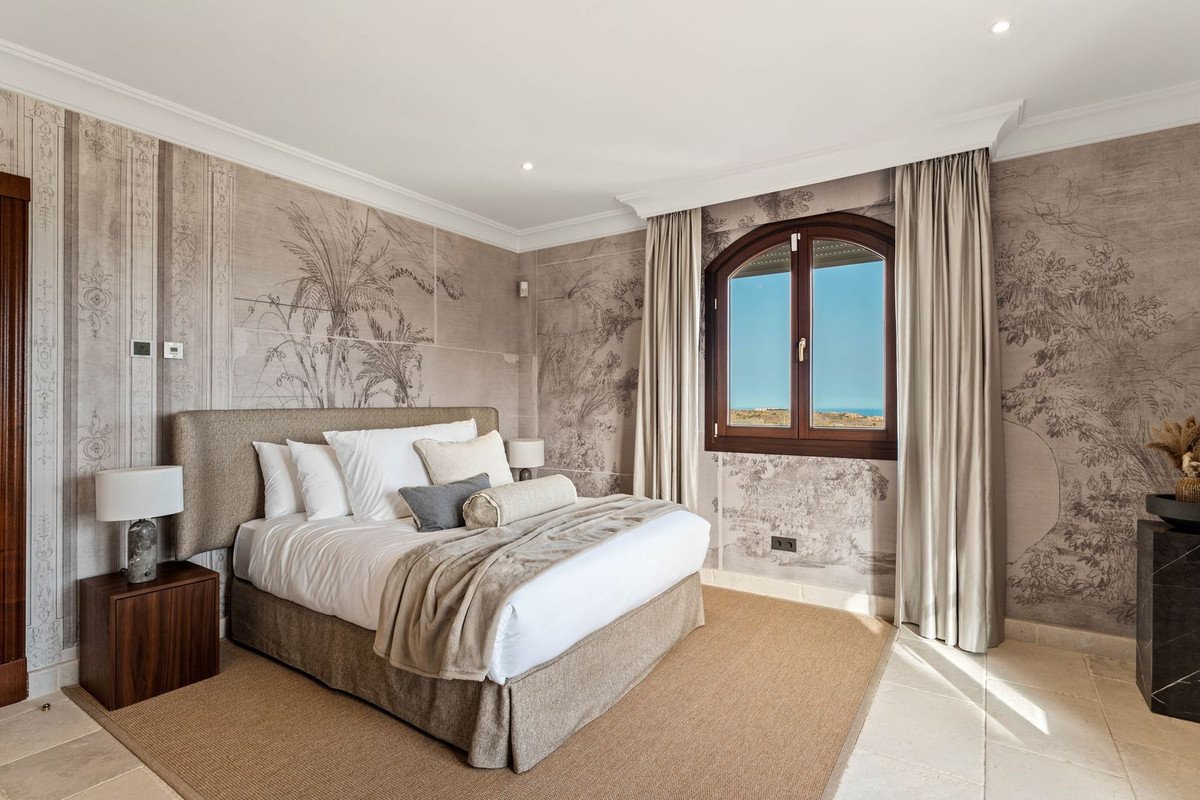 Bedroom featuring a large bed, decorative mural wallpaper, and a window with a sea view.