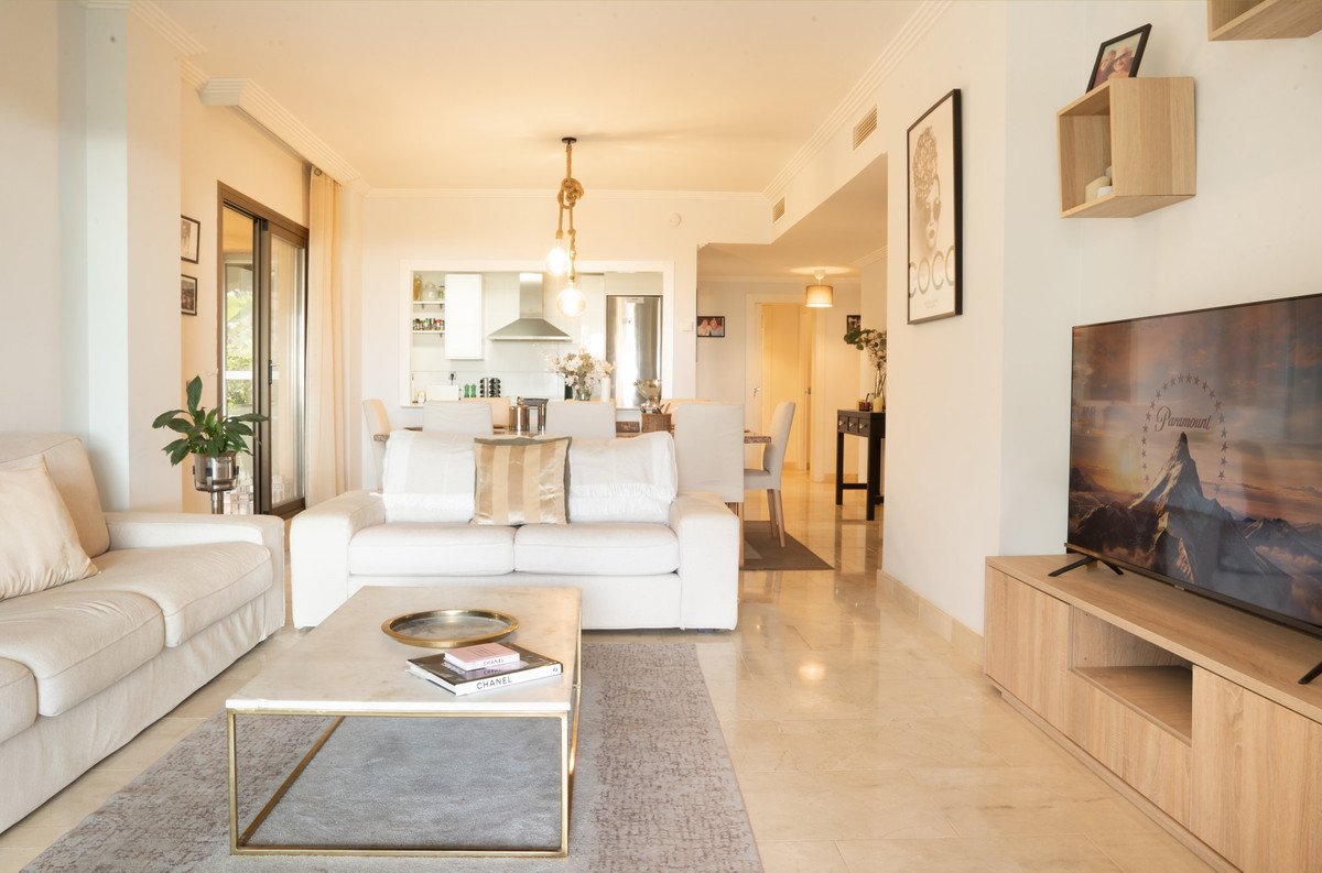 Modern living room with open plan layout, white sofas, and sliding glass doors
