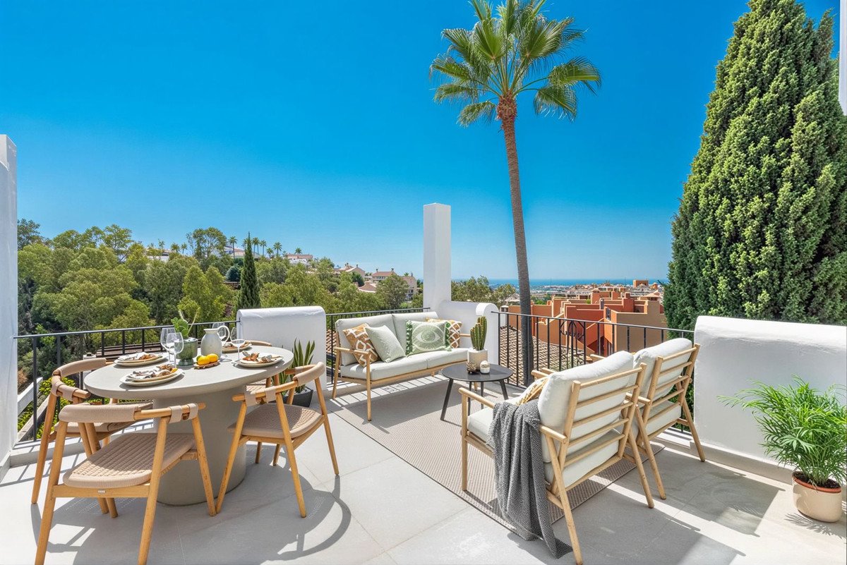 Modern terrace with dining set, sofas, and a distant sea view under a clear blue sky.