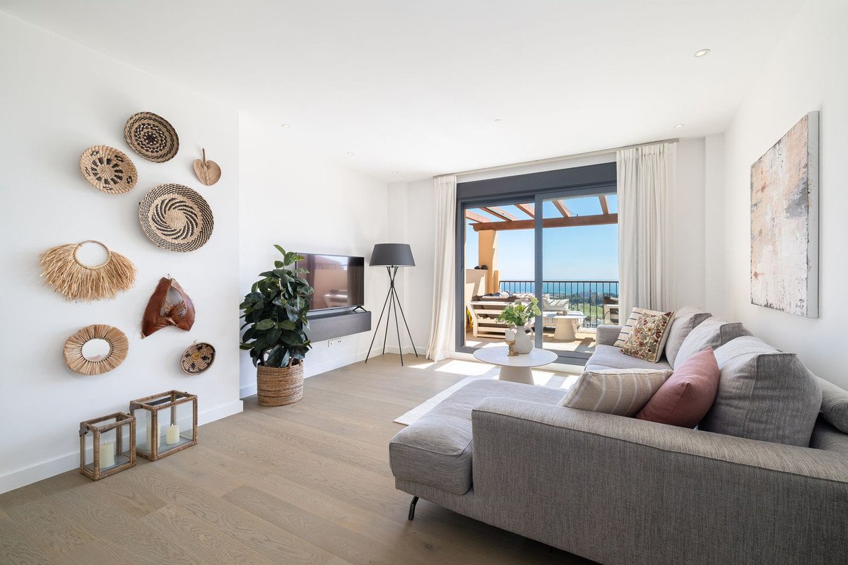 Modern living room with a grey sectional sofa, sea view from the balcony, and decorative wall art.
