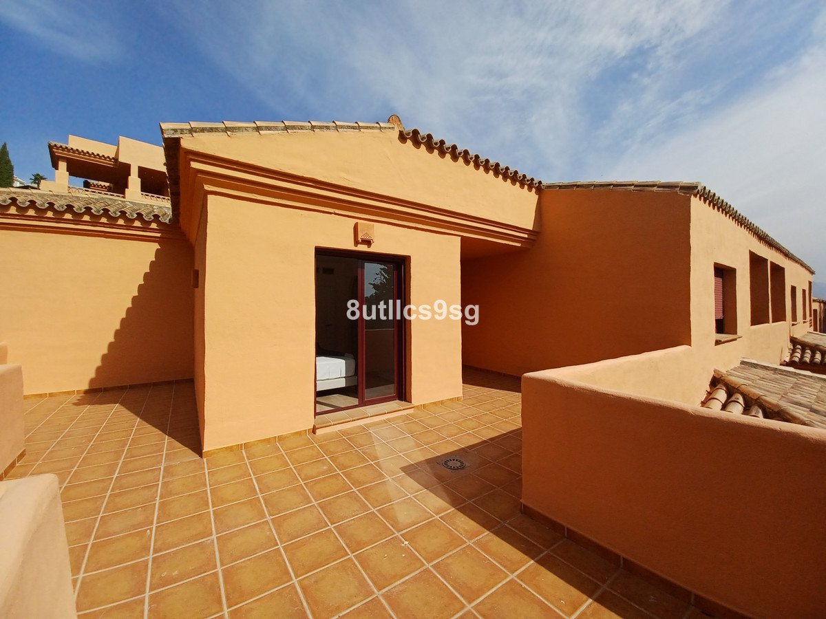 Exterior view of a tiled terrace with a glass door leading into a bedroom. Building has orange walls and a tiled roof.