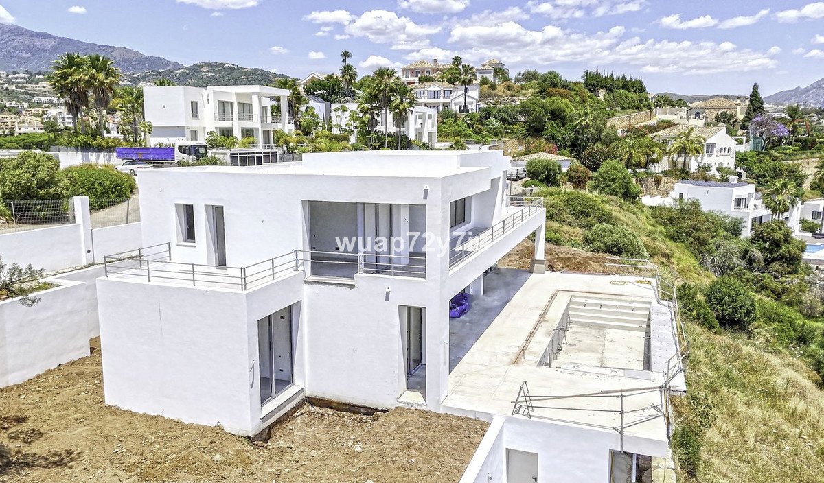 Modernes weißes zweistöckiges Haus mit Dachterrasse, Blick auf üppige grüne Landschaft.