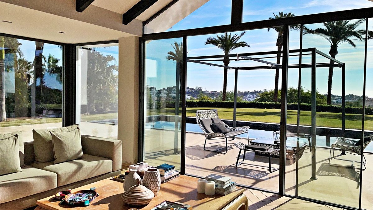 Modern living room with large windows overlooking pool and palm trees