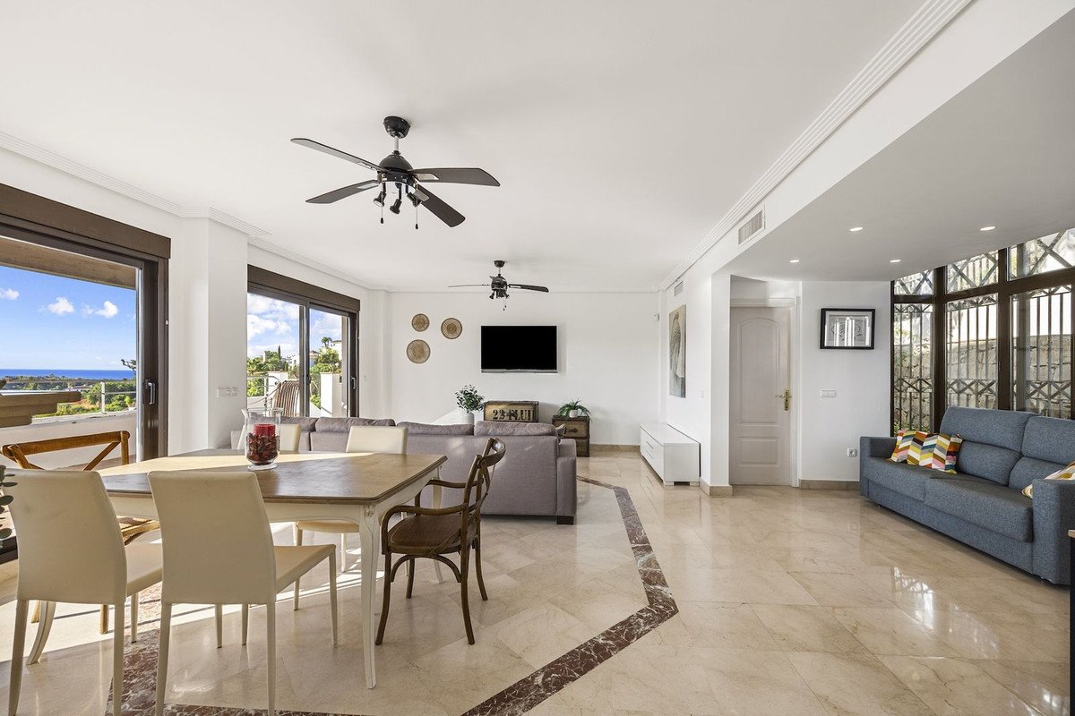 Spacious living and dining area with a sea view from the balcony, featuring ceiling fans and comfortable seating.