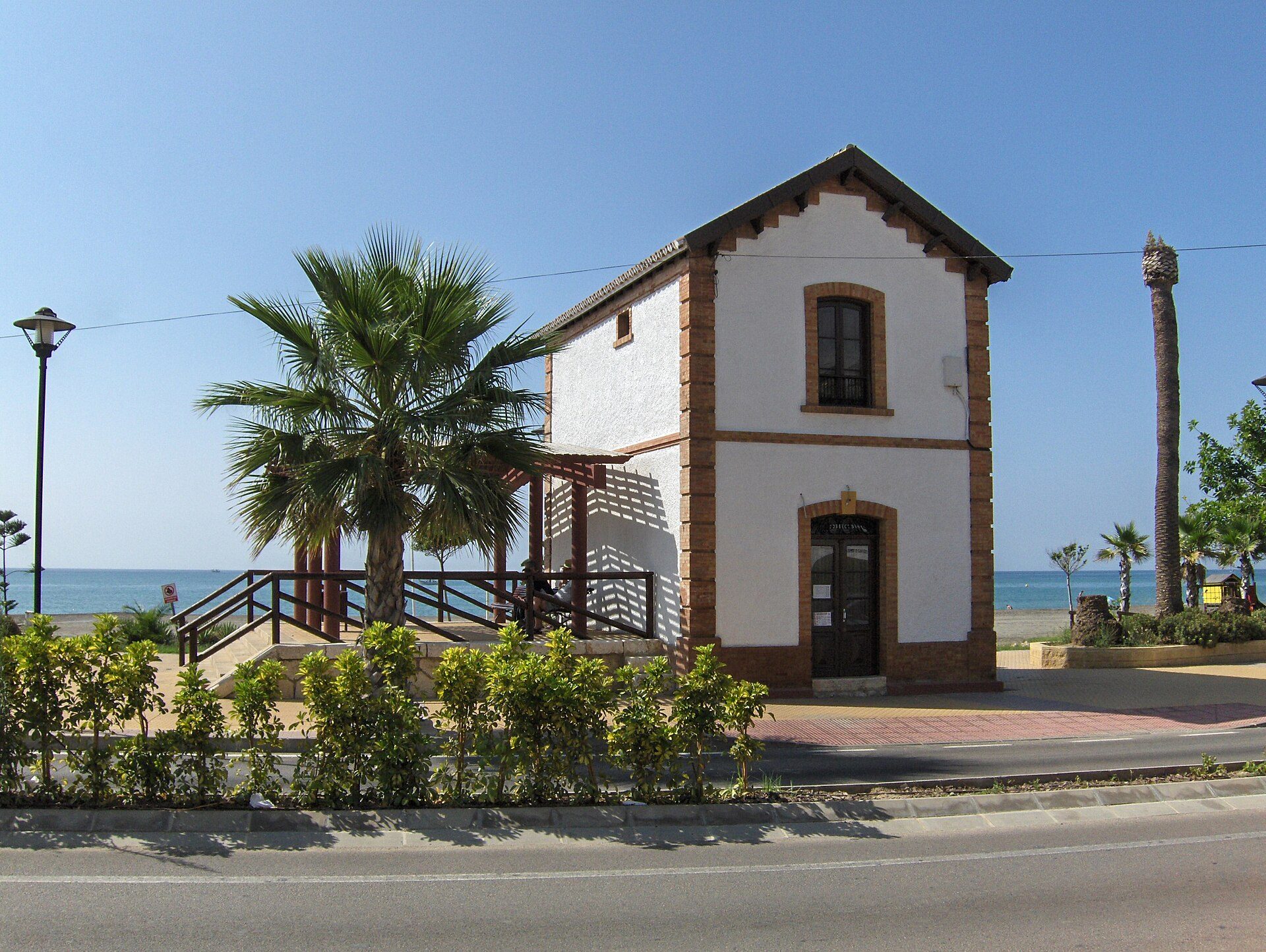 Cozy beachfront cottage with ocean view, featuring a balcony and palm trees.