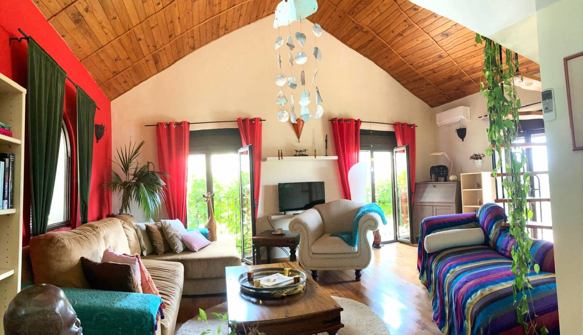 Eclectische woonkamerinterieur met hoog houten plafond en felle kleuren.