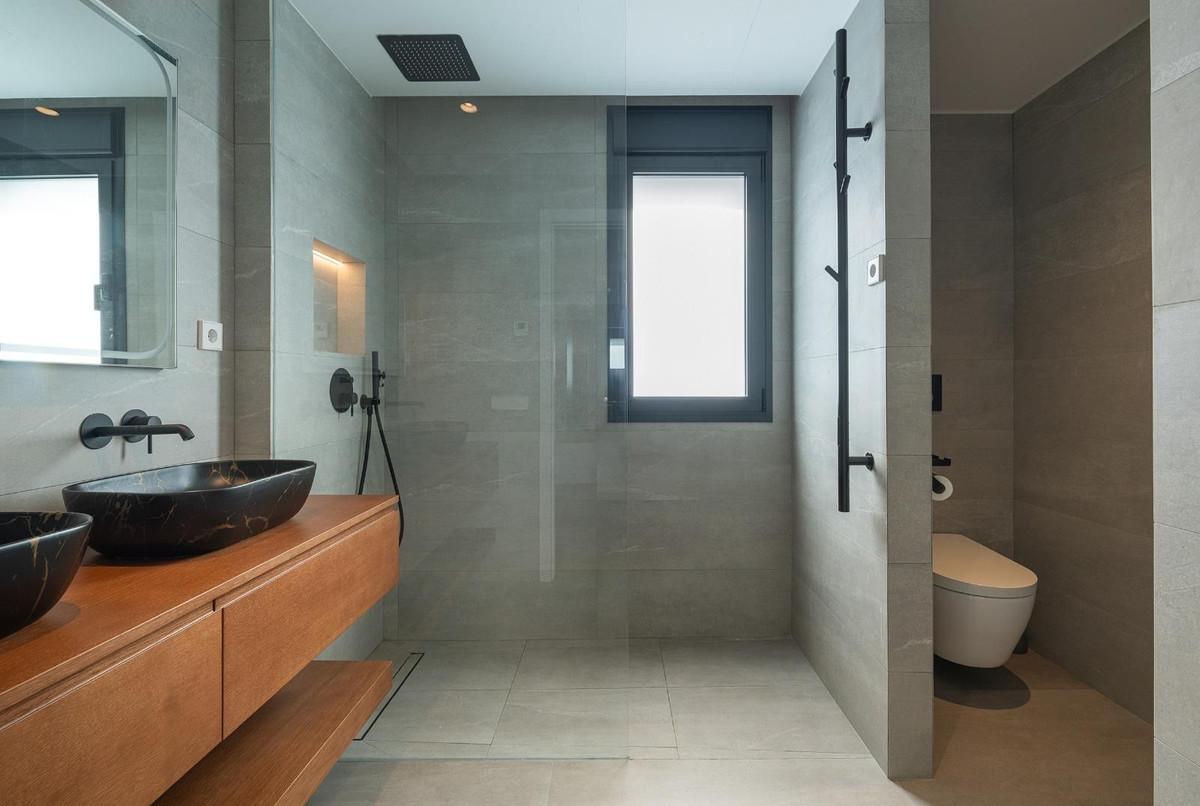 Moderne badkamer met houten wastafel en grijze tegels.