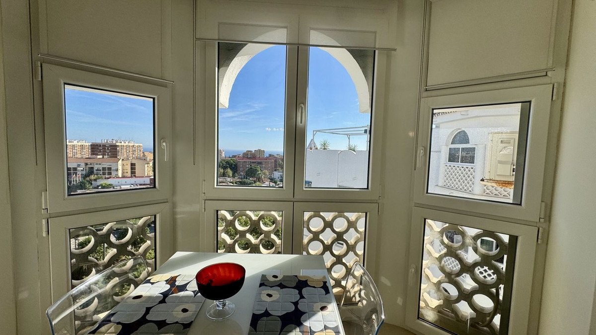 Dining area with large windows offering views of city buildings, the sea, and balconies with unique decorative grates.