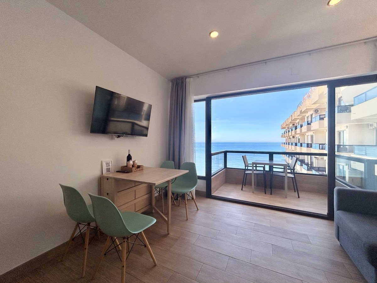 Modern living room with sliding glass doors opening to a balcony overlooking the ocean