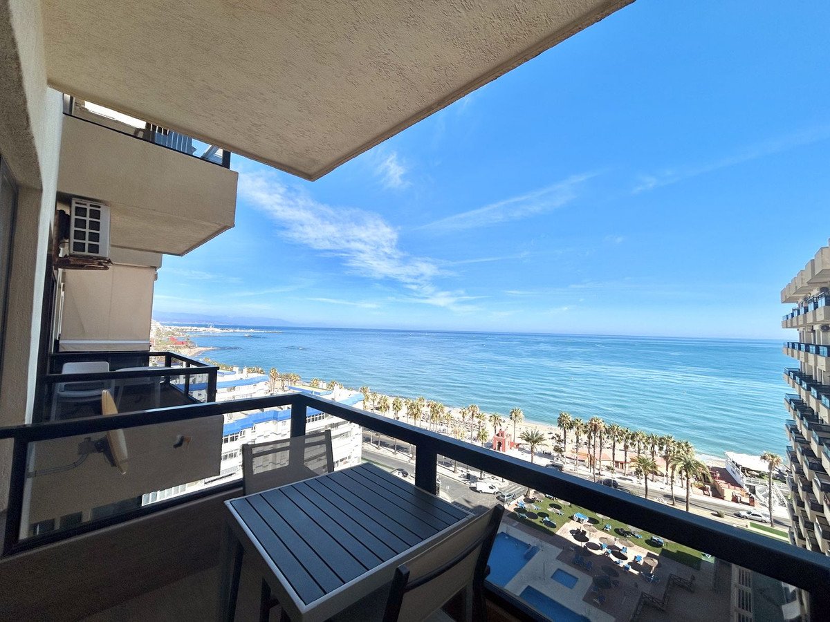Balcony with ocean view, palm trees, and outdoor seating