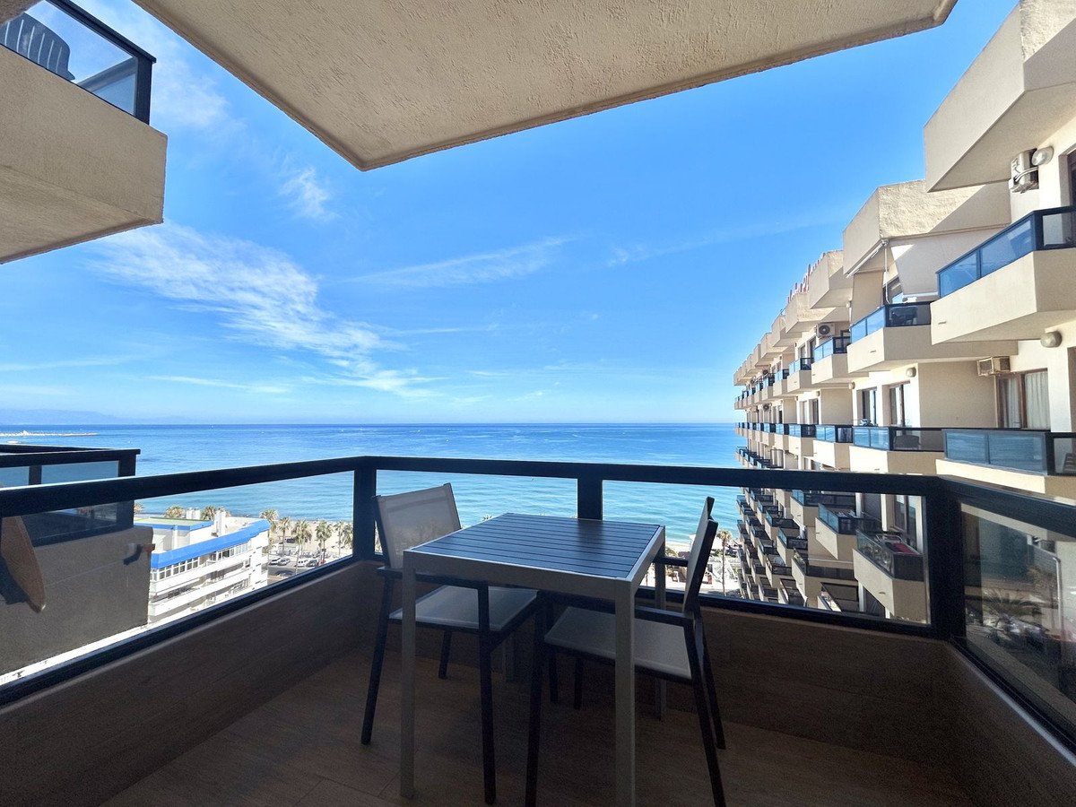 Balcony with table and chairs overlooking the ocean and adjacent buildings