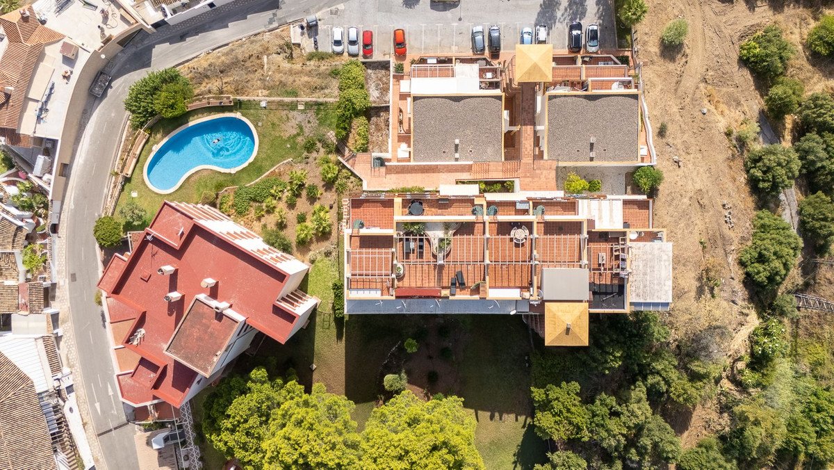 Aerial view of apartment buildings with a swimming pool and surrounding greenery. Outdoor terraces are visible.
