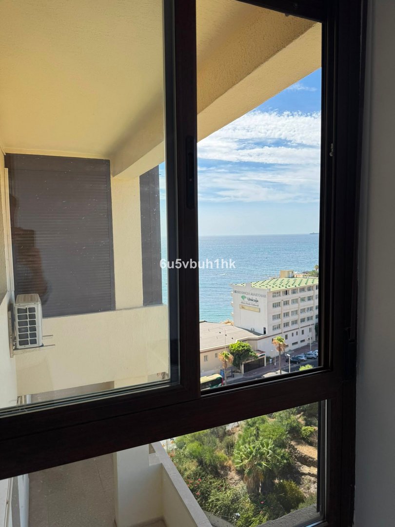 Apartment interior with large window overlooking ocean and city buildings