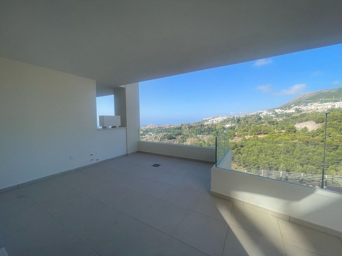 Spacious balcony with a modern design, offering panoramic sea and hillside views under a clear blue sky.