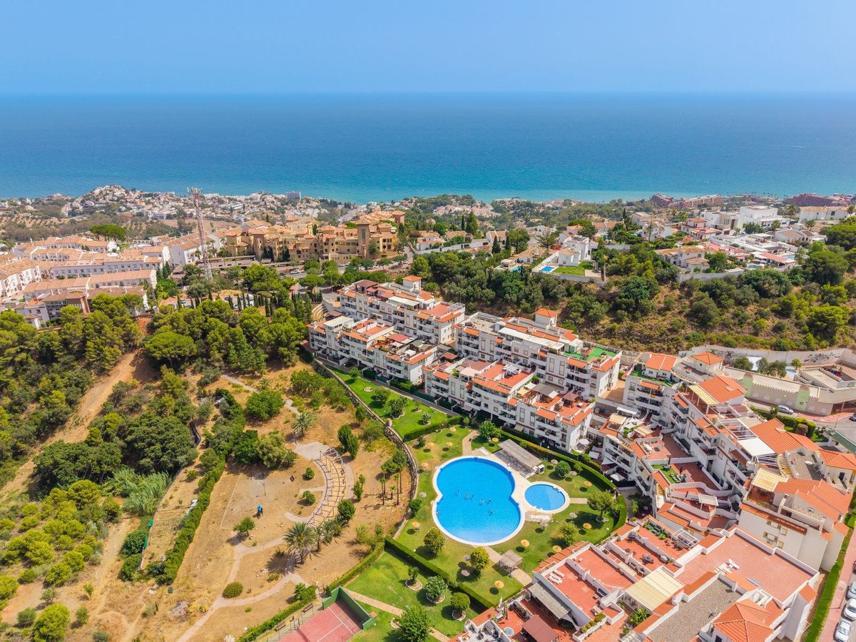 Aerial view of apartment complex with swimming pools and the Mediterranean Sea in the background.