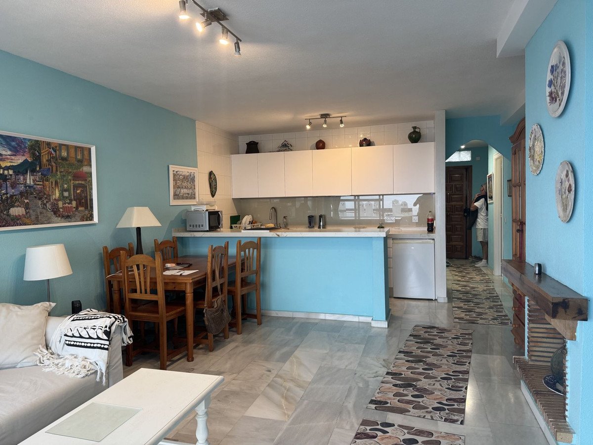 Modern living, dining, and kitchen area with blue walls, a dining table, and a sleek white countertop.