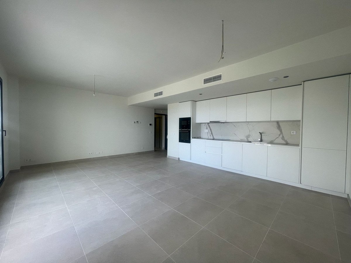 Modern open-plan living area with a sleek white kitchen, integrated appliances, and marble backsplash.