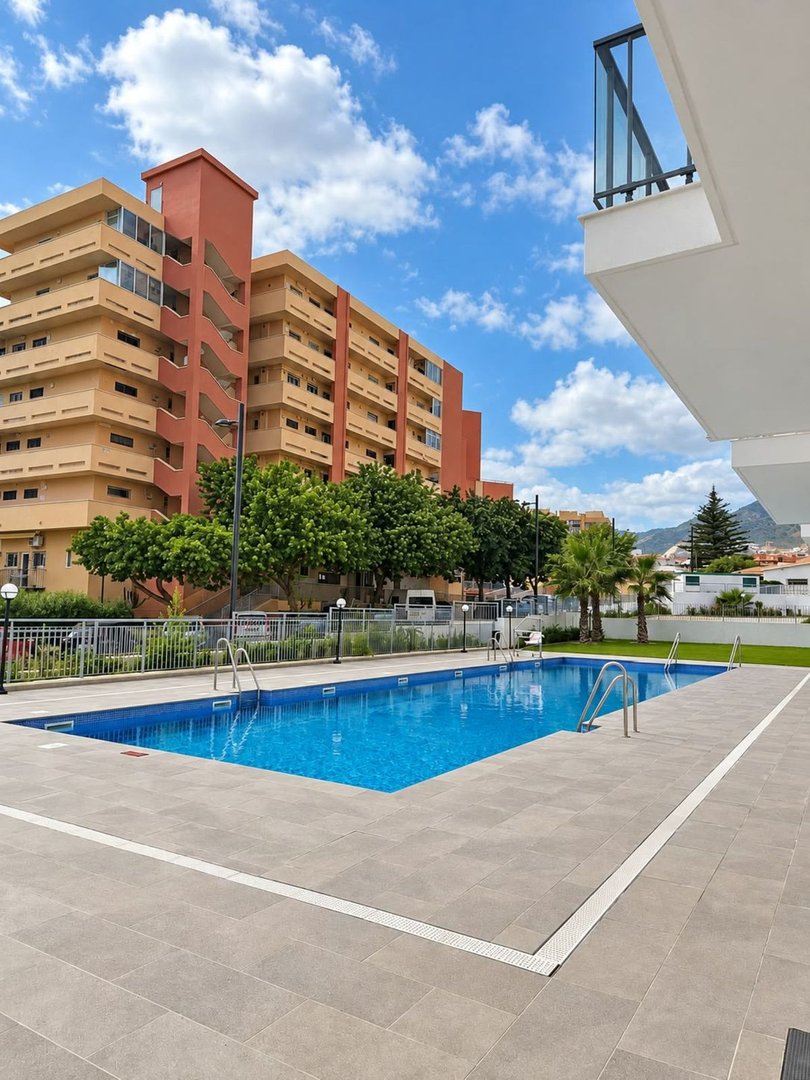 Outdoor swimming pool with tiled deck, surrounded by apartment buildings and greenery