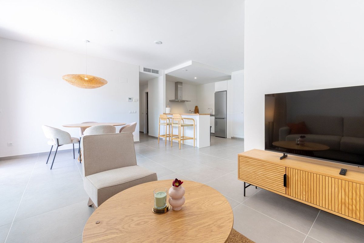 Spacious open-plan living, dining, and modern kitchen area with a TV, comfortable seating, and a stylish dining set.
