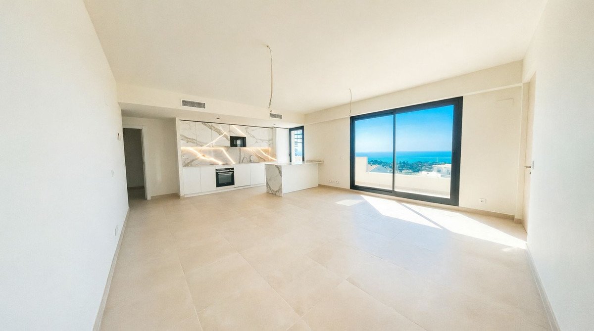 Modern open-plan living area and kitchen with a large window offering a stunning sea view.