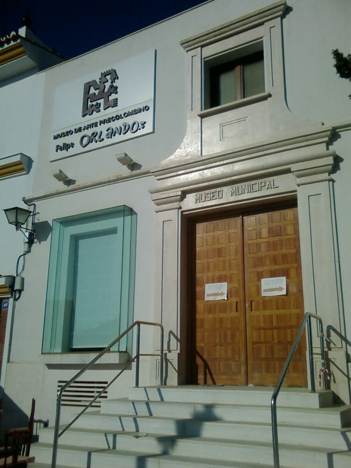 Exterior view of a municipal building with wooden doors and a sign reading "Museo Municipal.