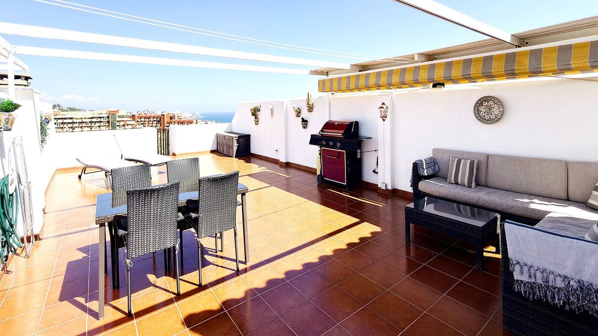 Spacious terrace with outdoor dining, seating area, barbecue grill, and lounge chairs overlooking the sea.
