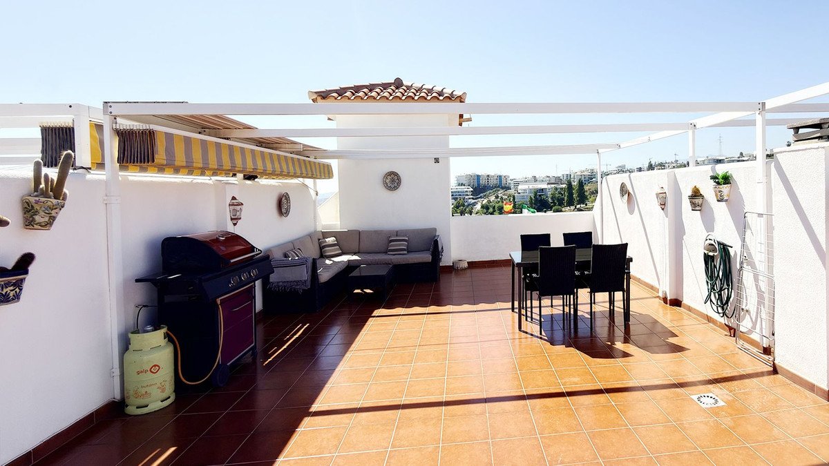 Spacious terrace with outdoor dining set, barbecue grill, and lounge seating, offering a town view under a pergola.