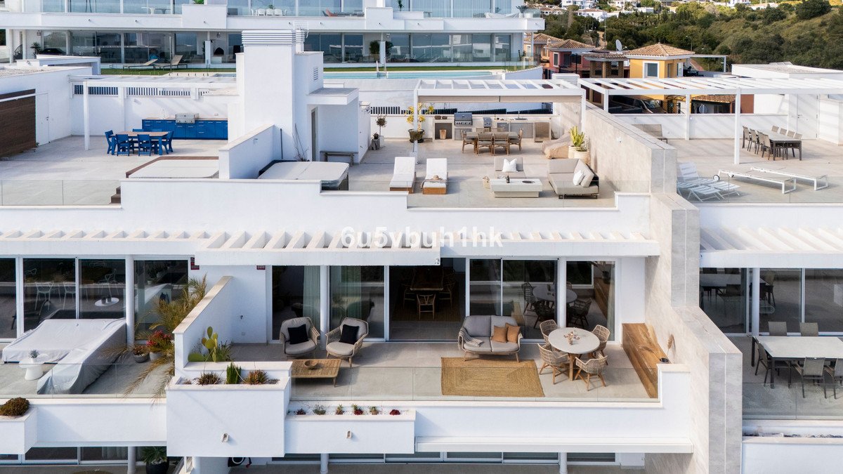 Modern rooftop terrace with outdoor dining, lounge seating, jacuzzi, and panoramic views of the sea and surrounding landscape.