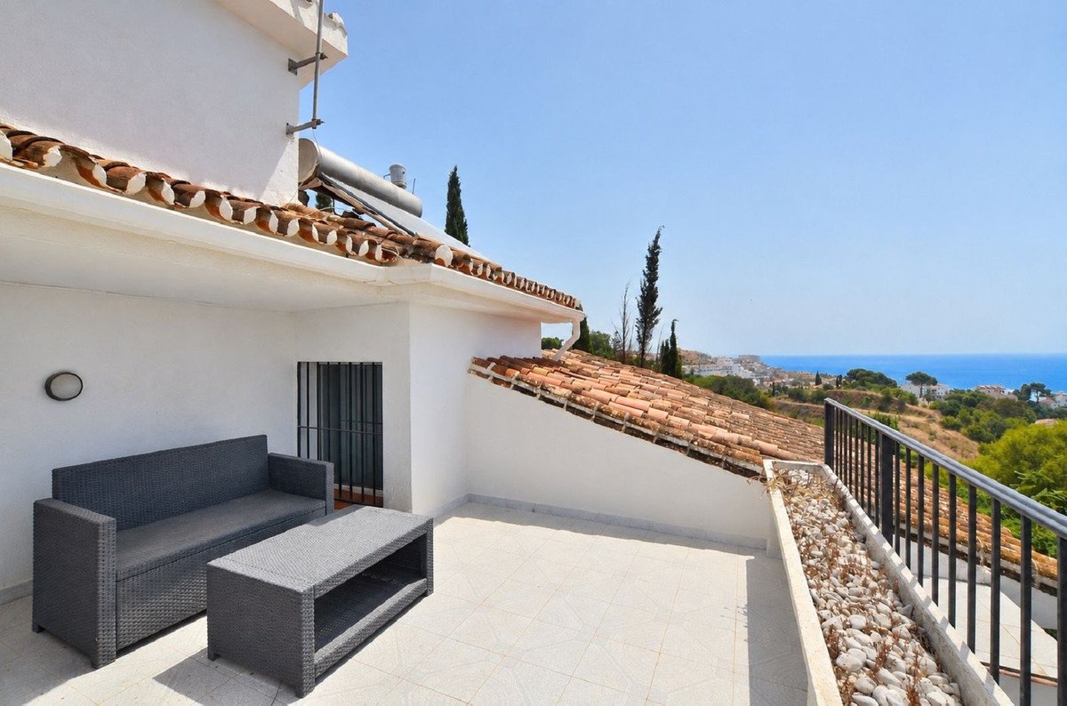 A spacious terrace with outdoor seating and a coffee table, offering a beautiful view of the sea and a coastal town.