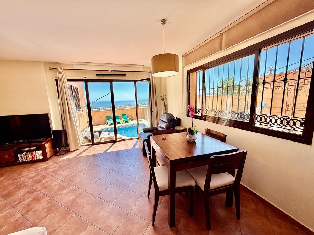 Living room with dining table overlooking a private pool and the sea through sliding glass doors.