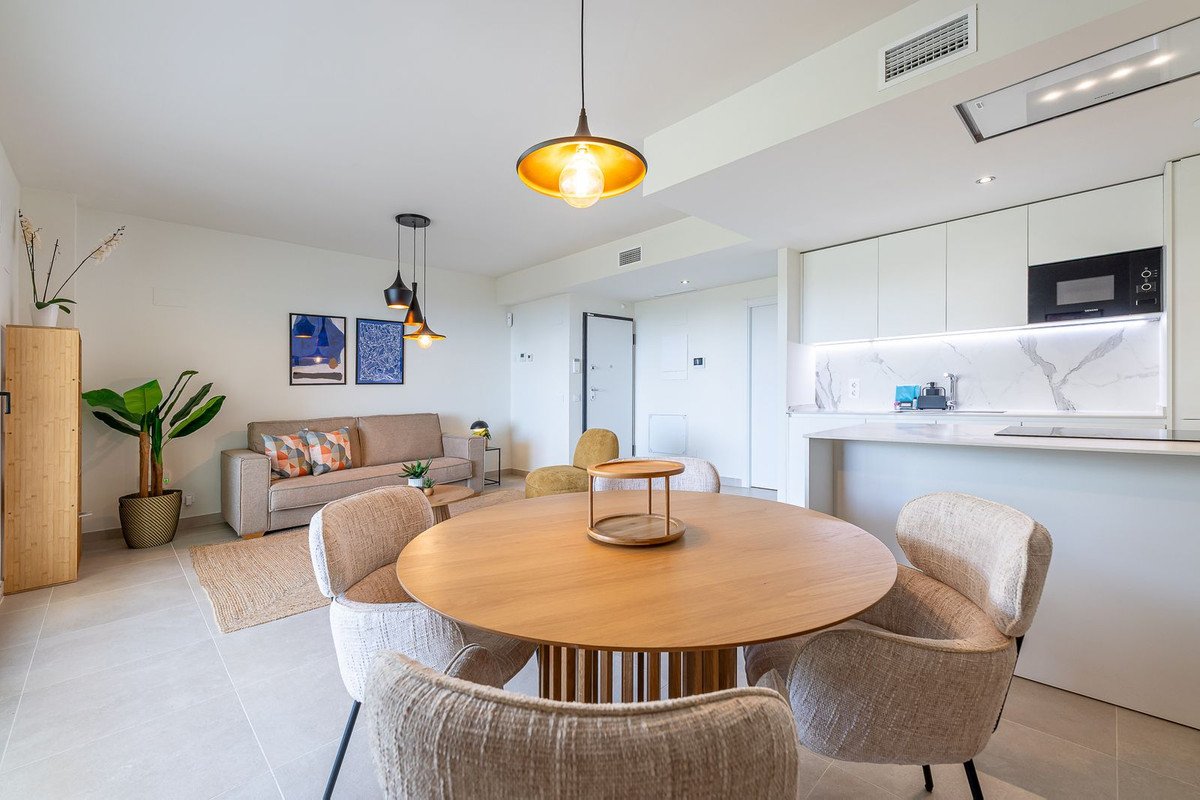 Modern open-plan living, dining, and kitchen area with a sofa, dining table, and contemporary kitchen counter.