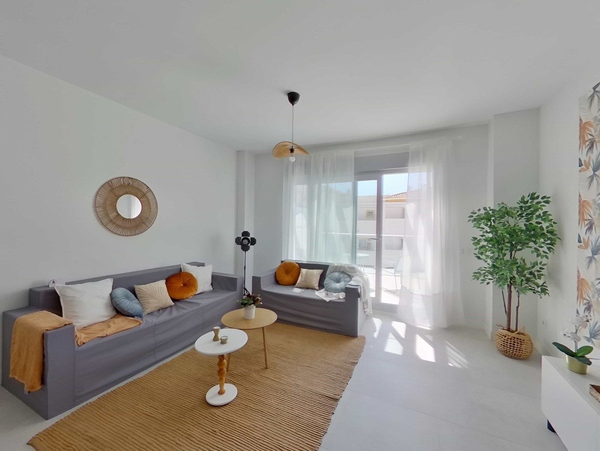 Modern living room with grey sofas, coffee tables, jute rug, and balcony access with natural light.