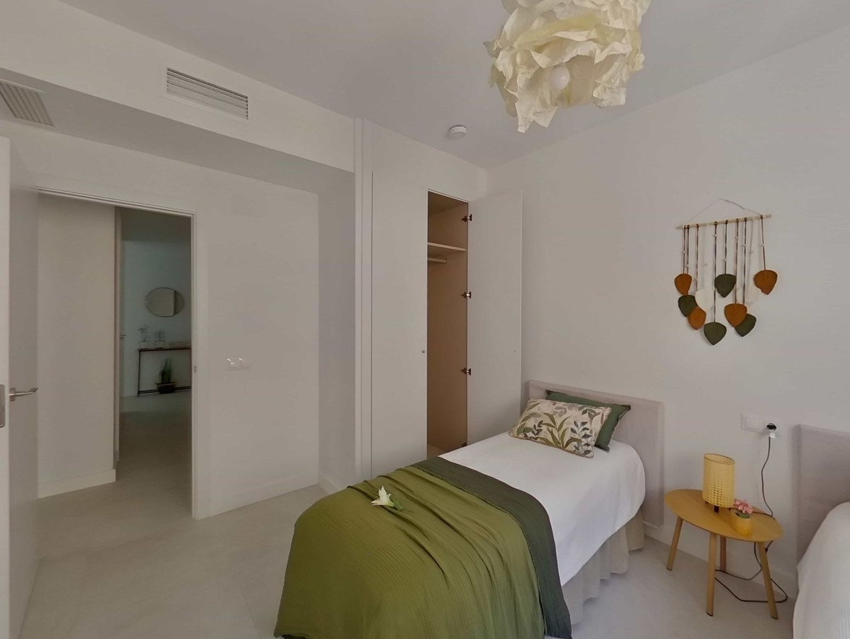 Modern bedroom with twin beds, green bedding, open closet, and a sliding door revealing another room.