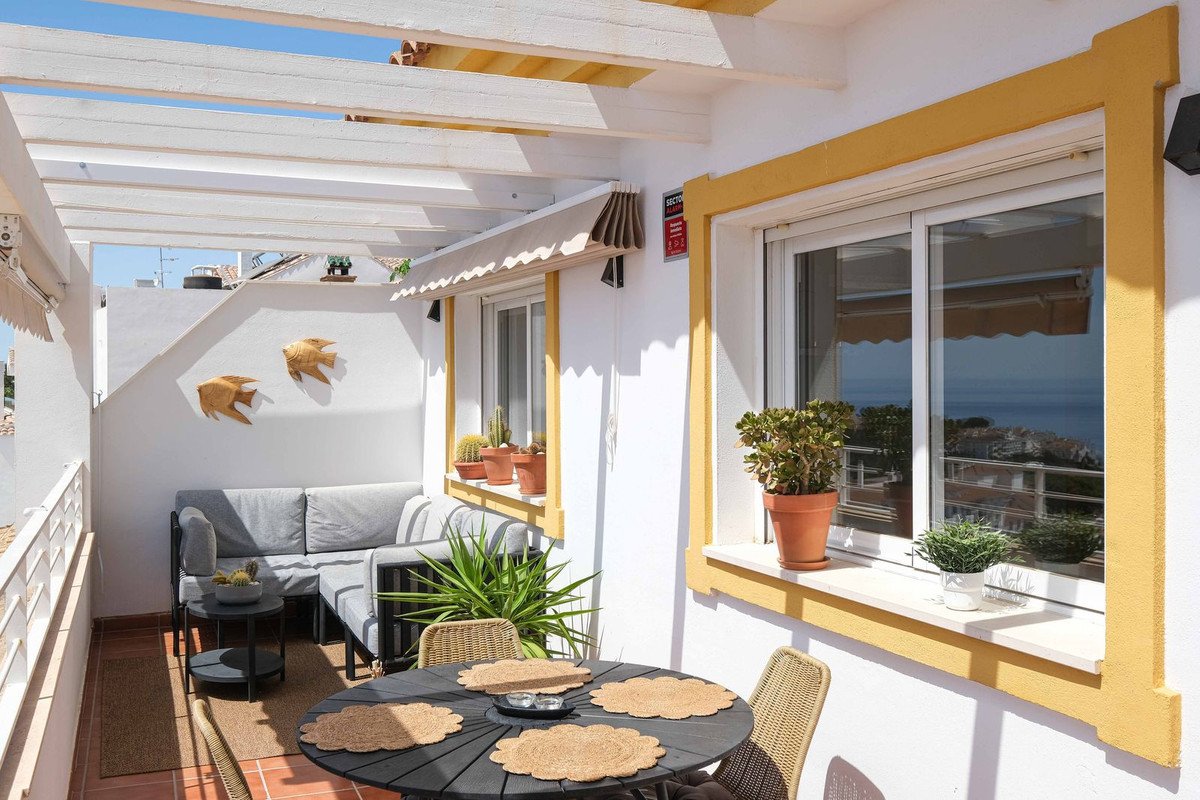 Sunny rooftop terrace with seating, dining table, and sea view.