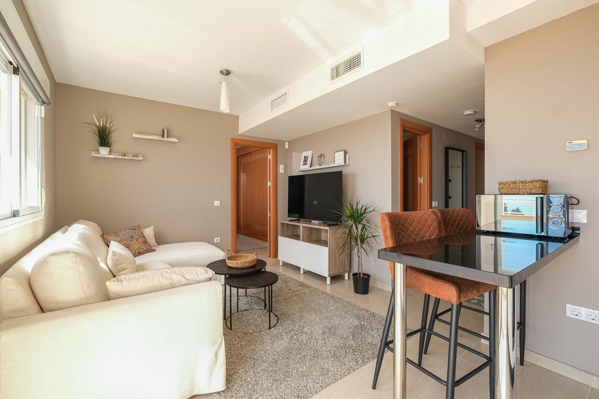Modern living room with white sofa, TV, and open kitchen area