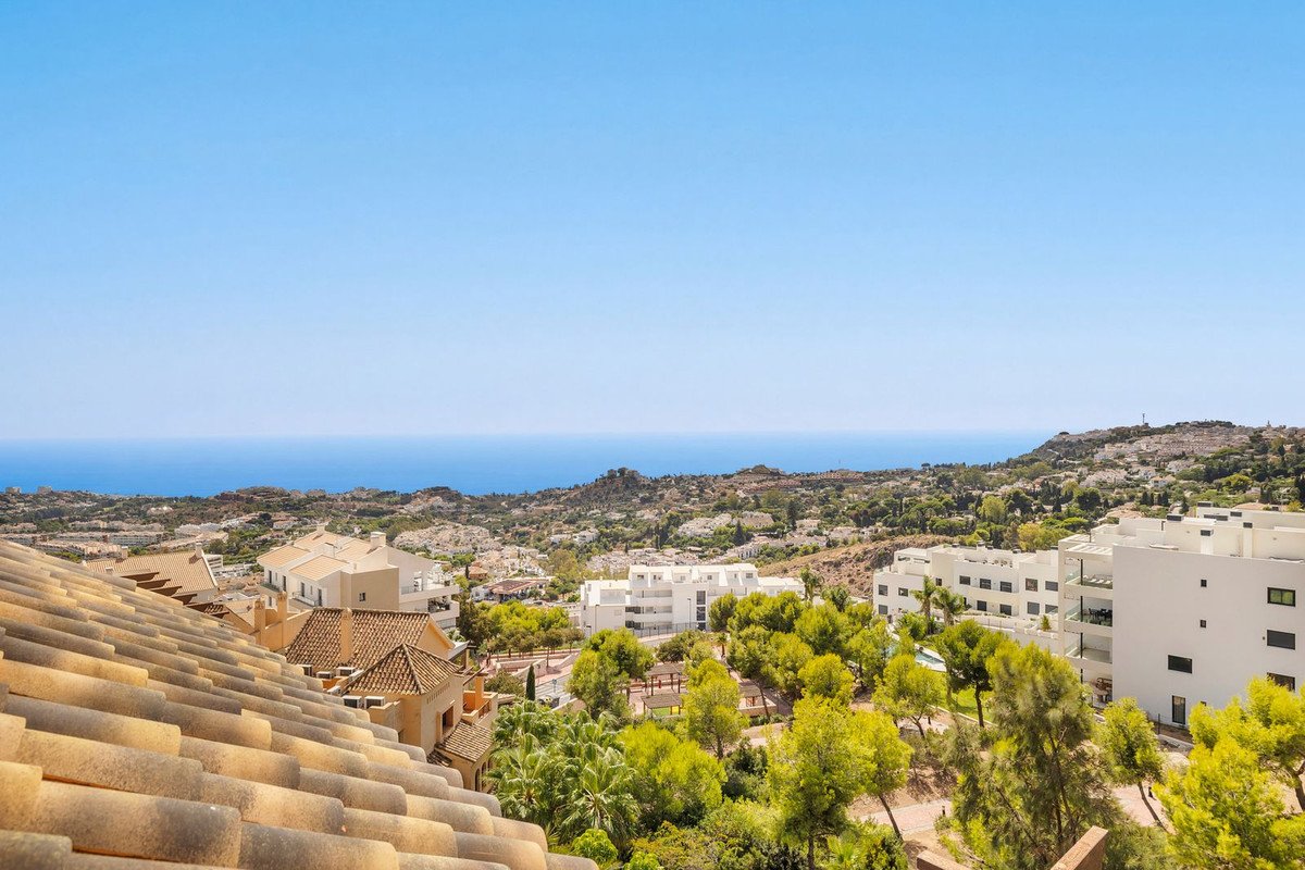 A view from a property terrace overlooking the sea, with surrounding buildings and greenery under a clear blue sky.