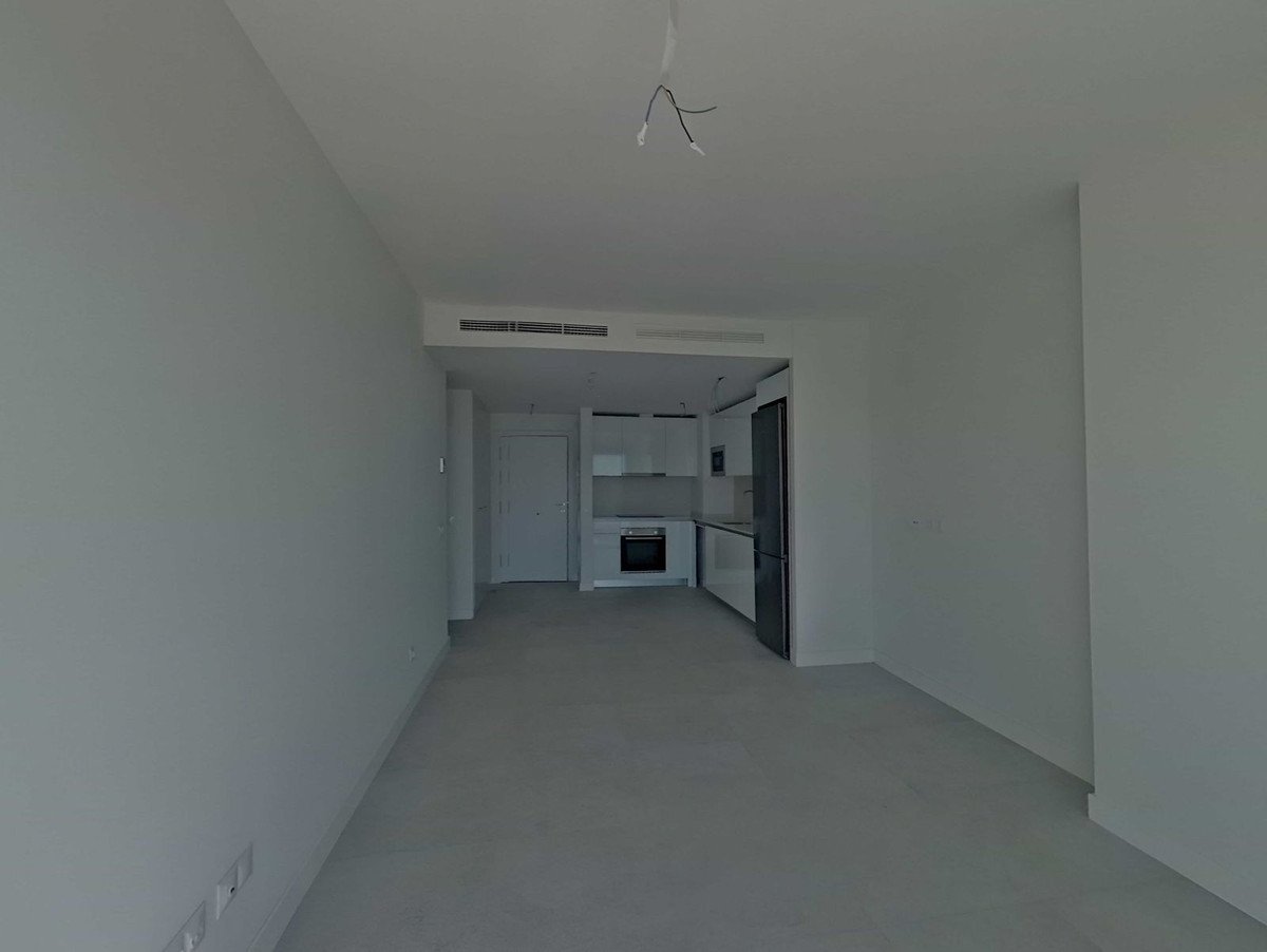 Spacious modern living area with an integrated kitchen featuring white cabinets and a refrigerator.