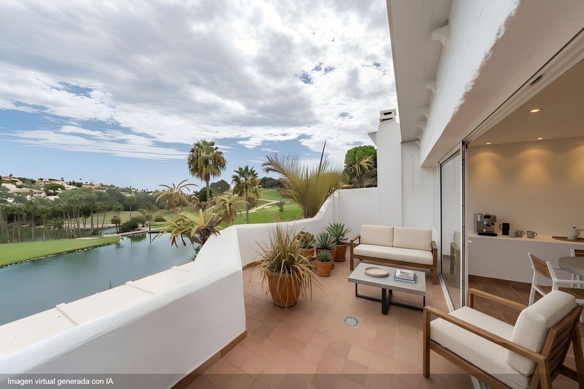 Terrace with seating and a view of a lake and golf course, featuring palm trees and lush greenery.