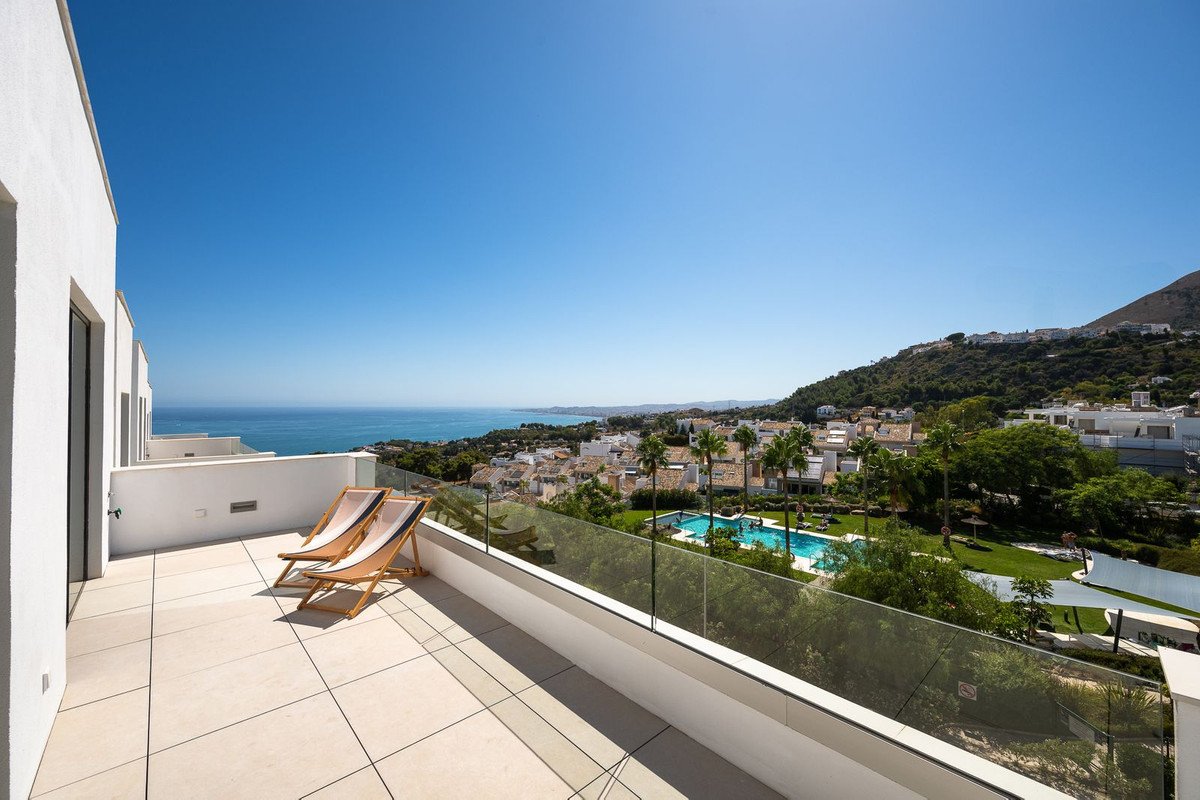 Spacious modern terrace with two lounge chairs offering panoramic views of the sea, pool, and surrounding cityscape.