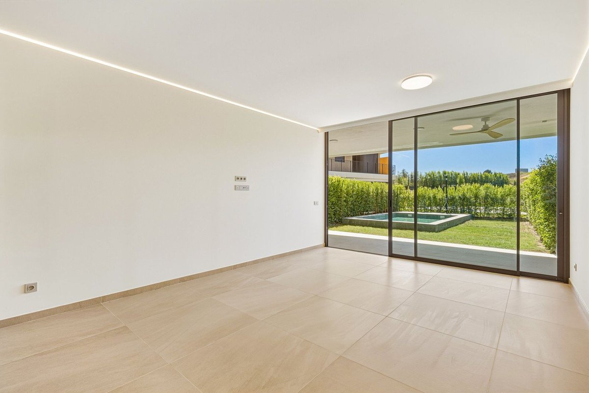 Modern living room with large sliding glass doors opening to a green garden and a small swimming pool.