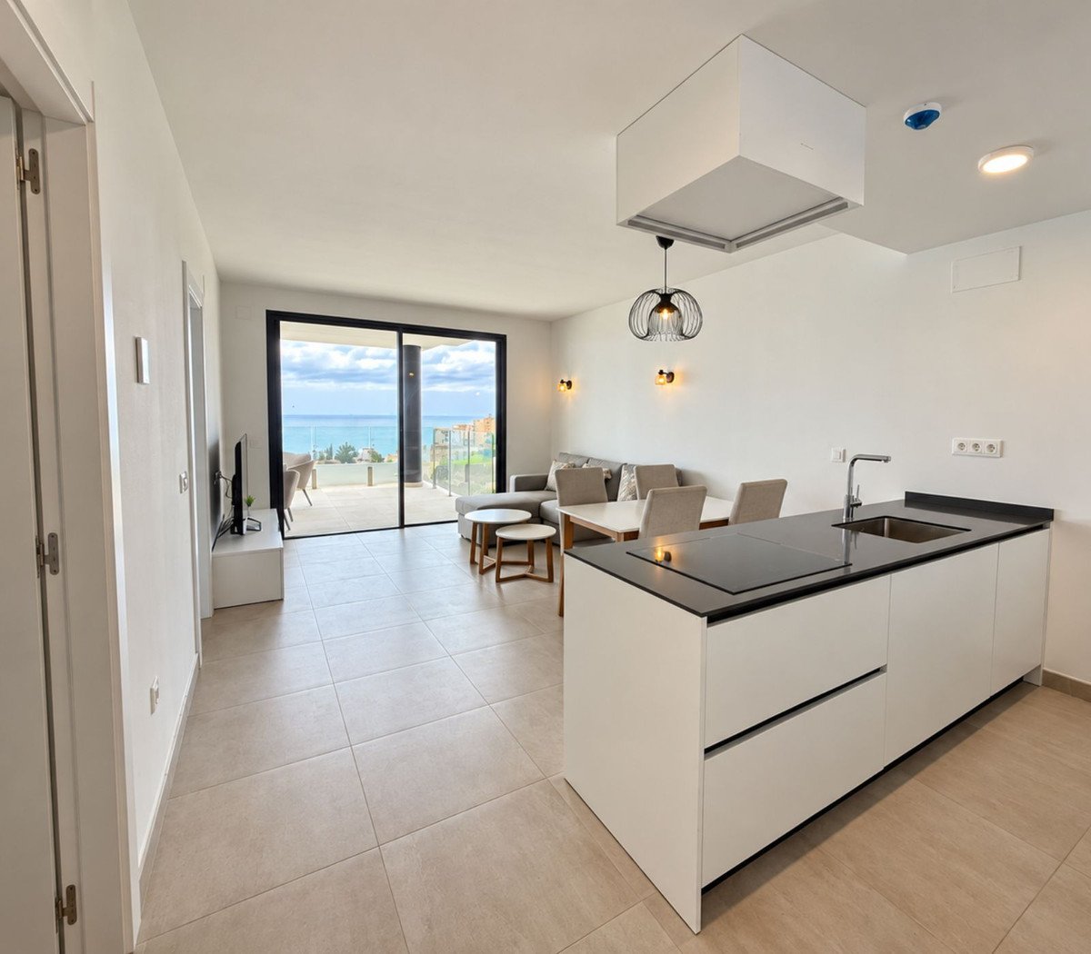 Modern living area with a sleek kitchen, comfortable seating, and a stunning sea view through large glass doors.
