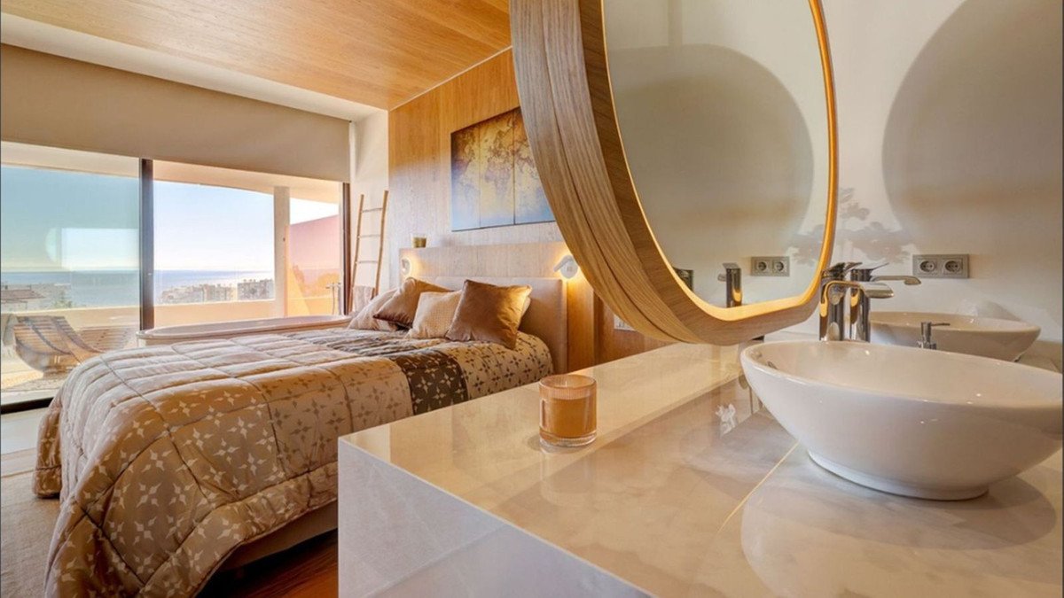 Master bedroom with sea view and modern bathroom featuring a large mirror and vessel sink