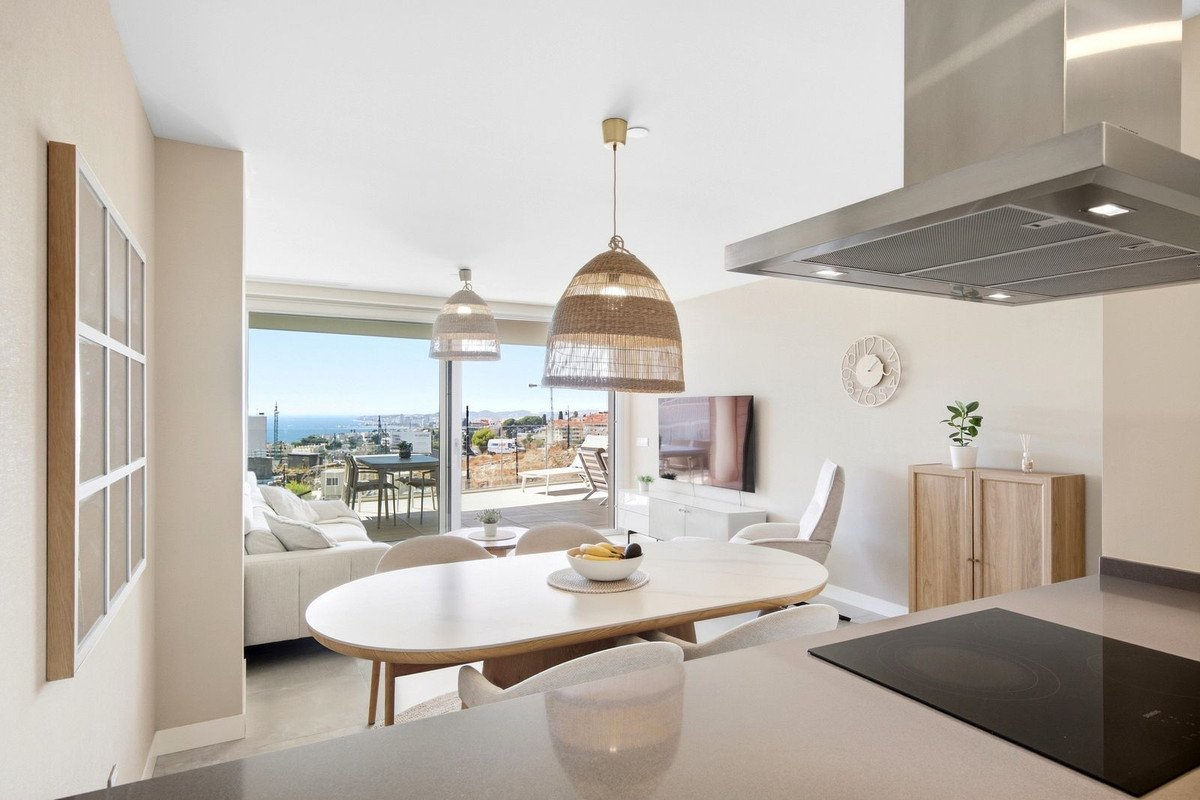 Modern open-plan living and dining area with a large window offering a panoramic view of the sea and cityscape.