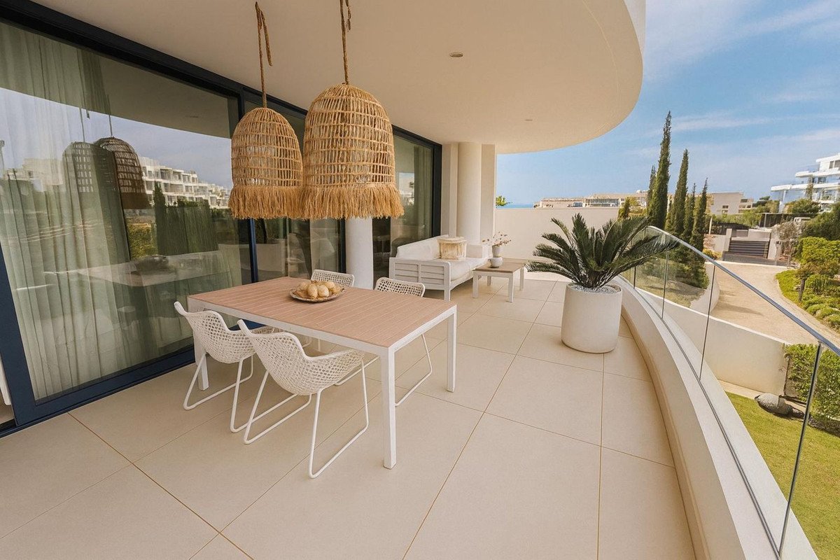 Modern terrace with dining set and lounge area, offering a sea view and lush landscaping.
