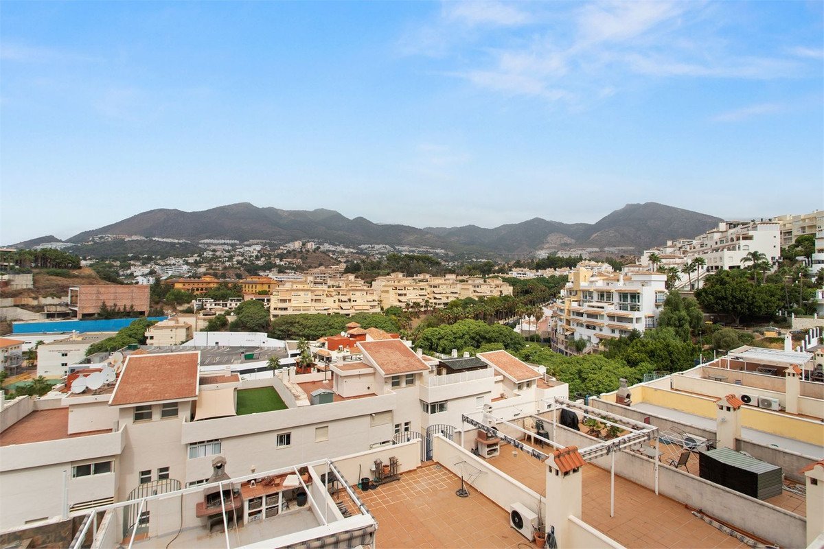 Rooftop terrace with outdoor kitchen and barbecue, offering panoramic views of mountains and cityscape.