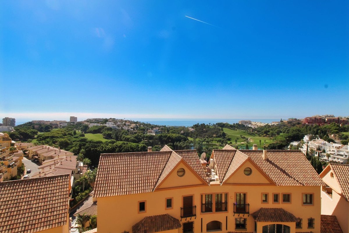 View from property overlooking golf course, rooftops, and the sea under a clear blue sky.