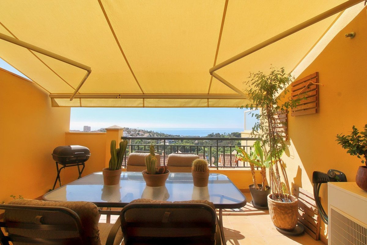 Terrace with dining table, chairs, grill, and potted plants offering a beautiful sea view.
