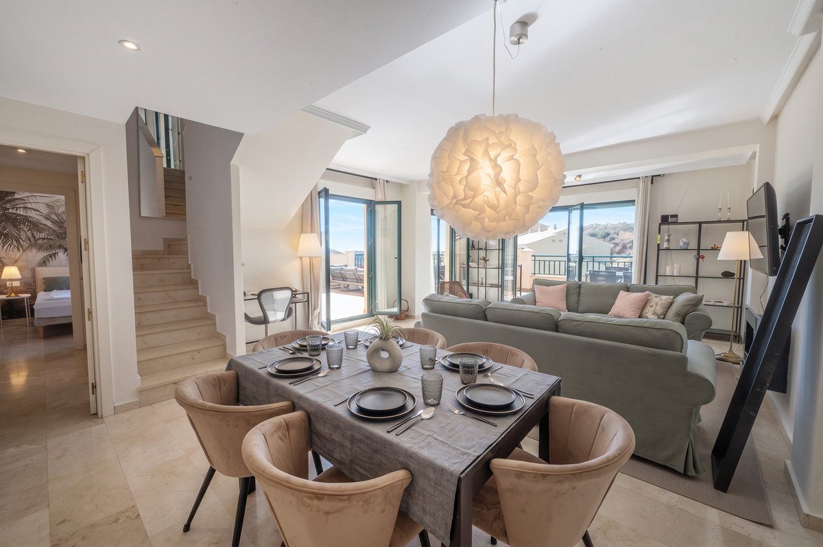 Open-plan living and dining area with sea view, modern decor, and large windows.