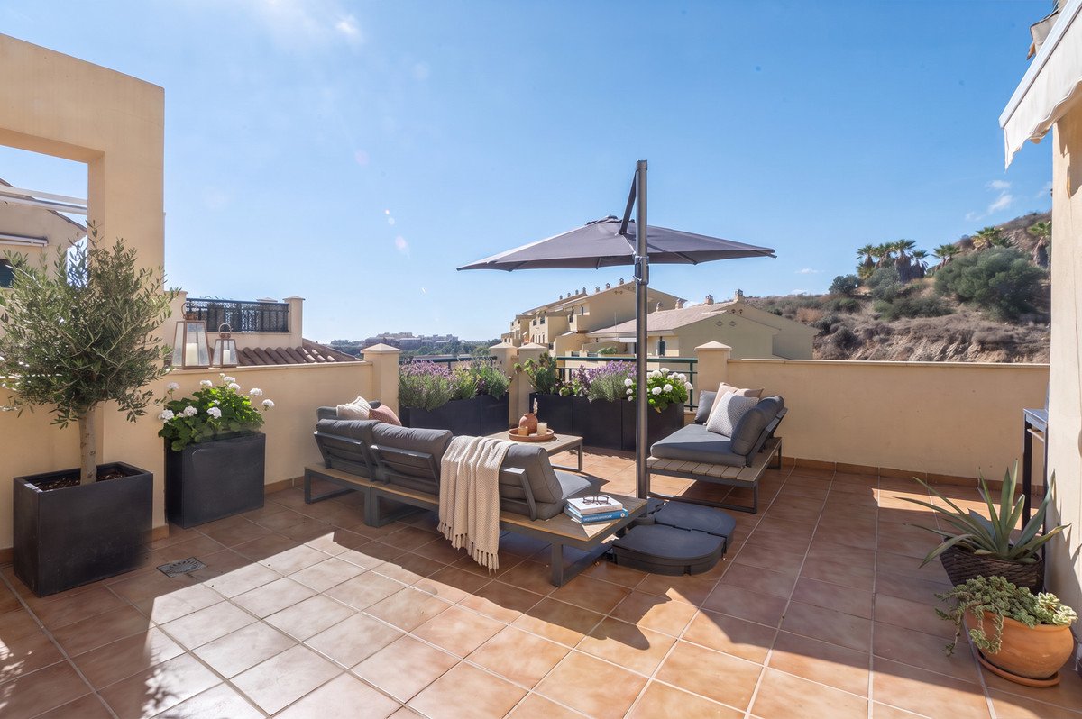 Rooftop terrace with outdoor seating, umbrella, and scenic hillside view